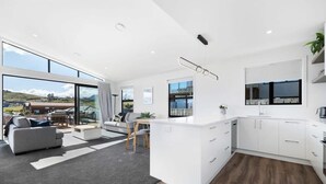 Une cuisine moderne avec des meubles blancs, un îlot central et un coin repas comprenant un canapé et une table.