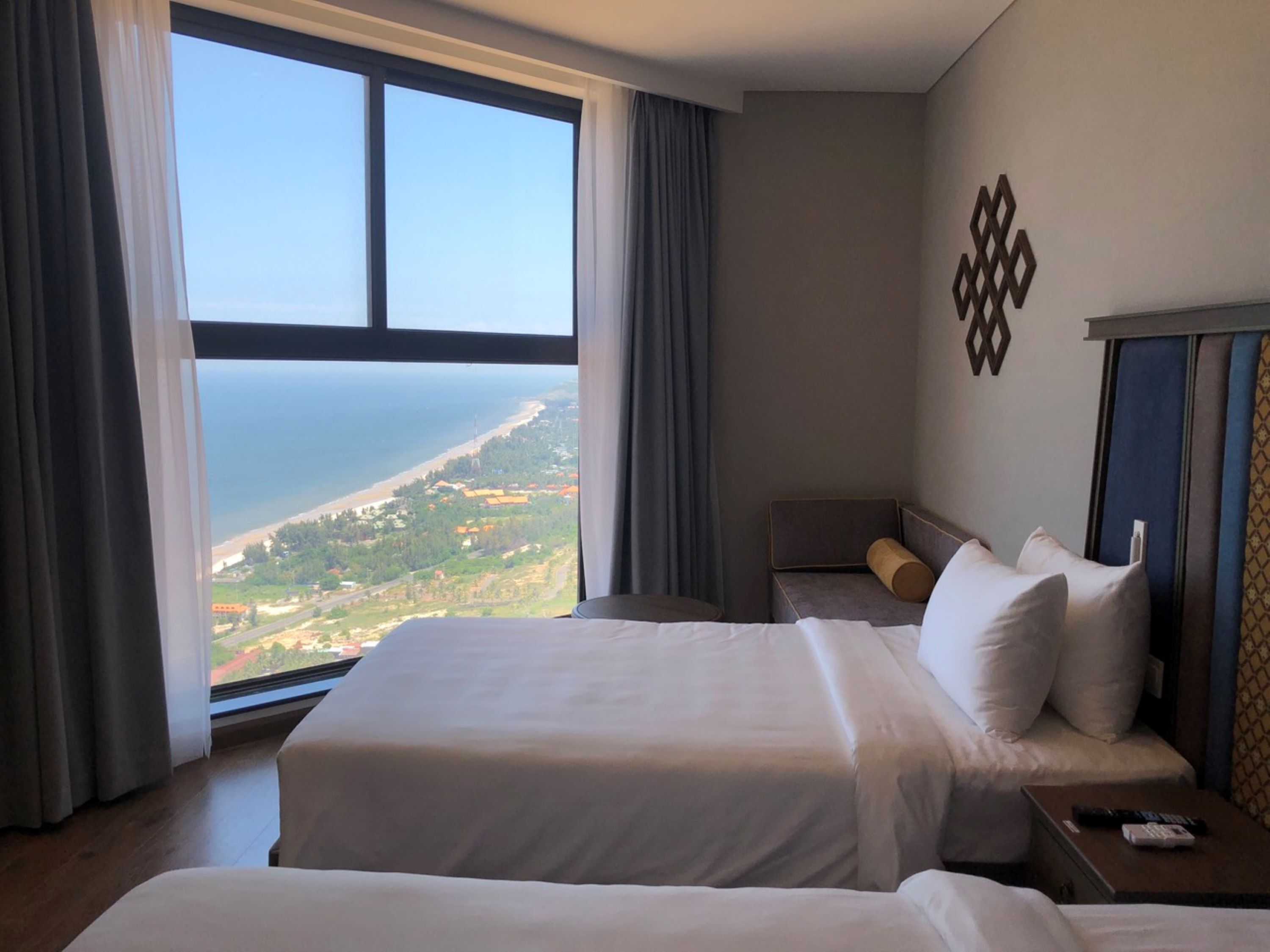 Ein Hotelzimmer mit zwei Betten, Meerblick und einer Wanddekoration.