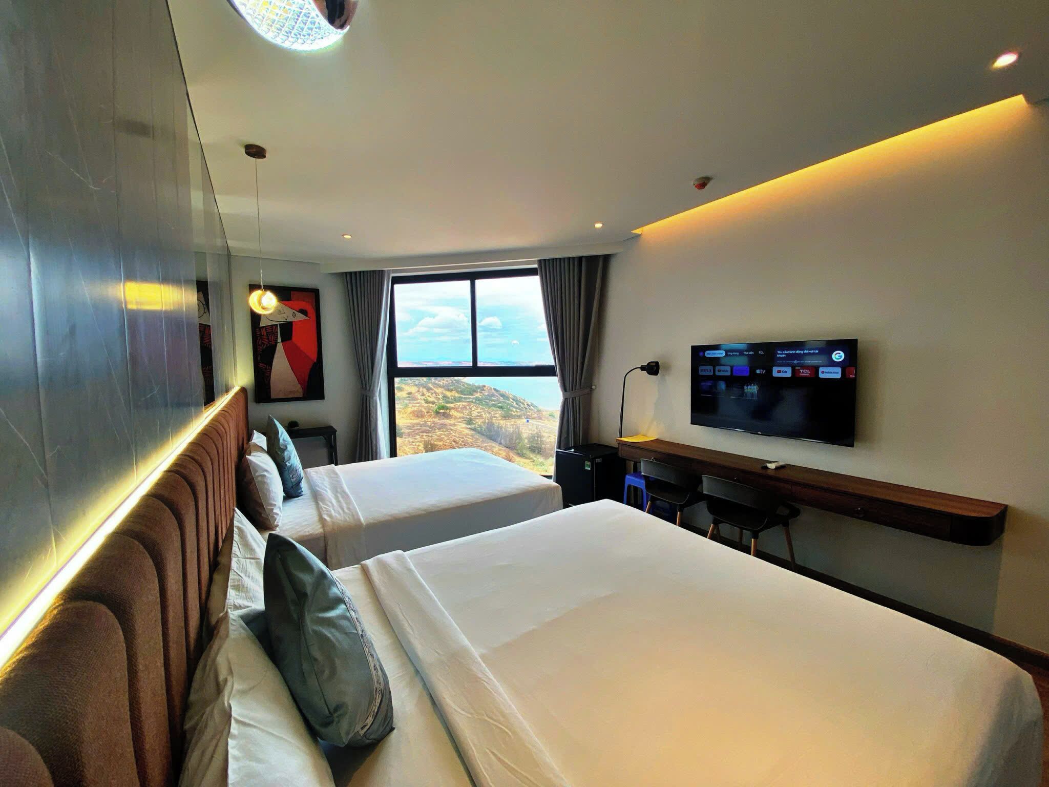 A hotel room with two beds, a TV, and a desk.