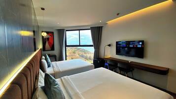 A hotel room with two beds, a TV, and a desk.