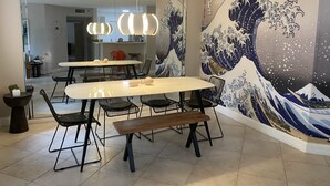 A dining area with a large table, chairs, and a mural of a wave. - Exclusive Yacht Club Condo 10 Min to the Beach (Miami)