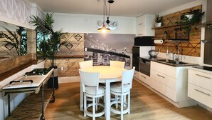 A modern kitchen with a central island, white cabinetry, and a cityscape mural on the wall. - 1 - BR Travellers  Basement Suite.NO Cleaning fee, Sumas Mountain Rd,Abbotsford (Abbotsford)
