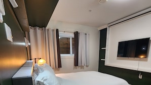 A modern bedroom with a bed, bedside table, lamp, curtains, window, and a TV mounted on the wall. - 1 - BR Travellers  Basement Suite.NO Cleaning fee, Sumas Mountain Rd,Abbotsford (Abbotsford)