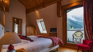A bedroom with a bed, a desk with a lamp, a chair, a TV, and a balcony with a chair.