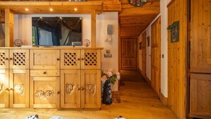 A wooden interior with a central wooden cabinet featuring animal carvings, a television, and a decorative plate on the wall.