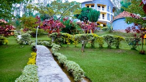 Un jardin bien entretenu, avec un chemin qui mène à un bâtiment doté de plusieurs balcons.