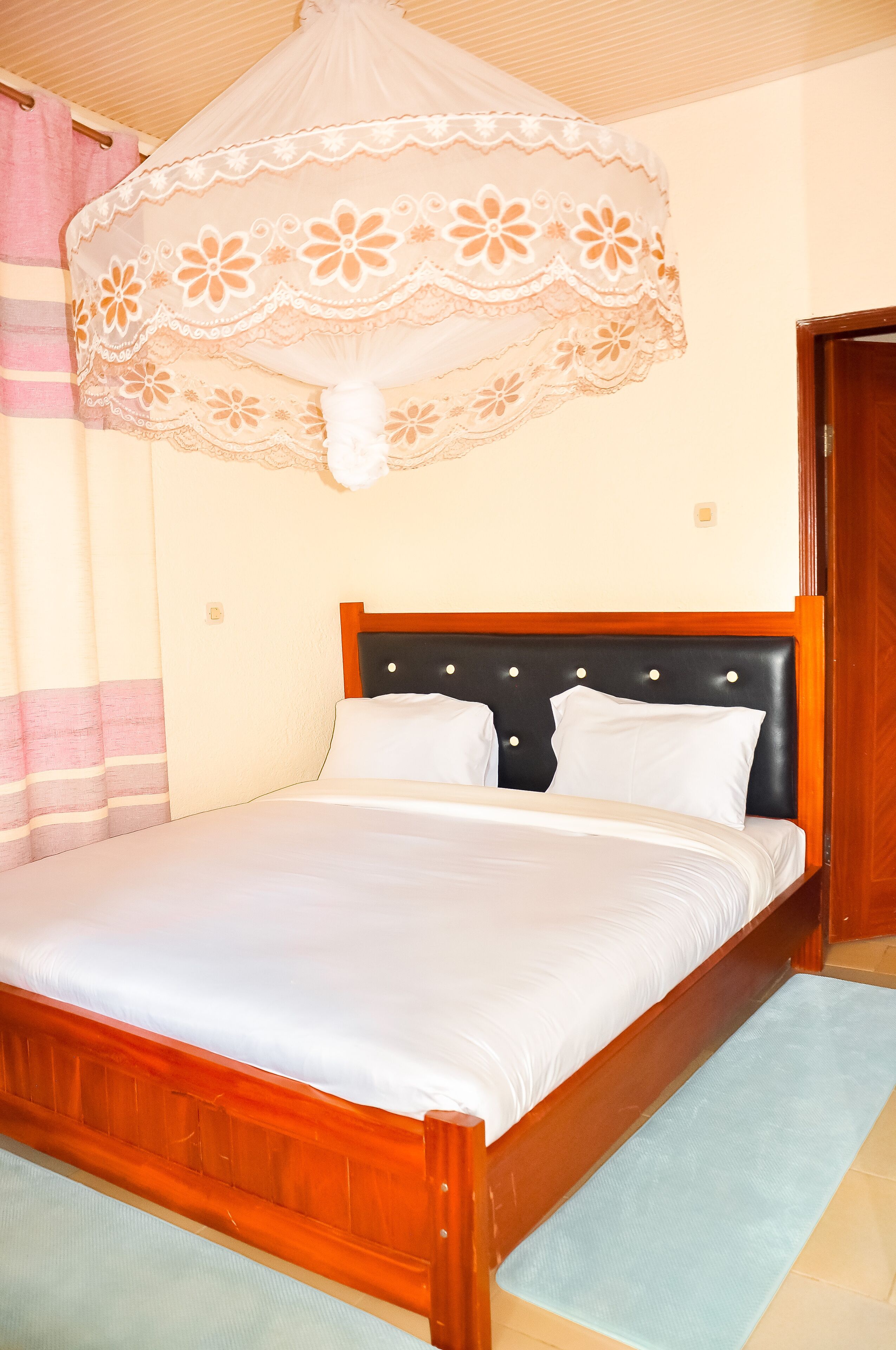 Een netjes opgemaakt bed met een houten hoofdbord, een witte dekbedovertrek en een decoratief baldakijn.