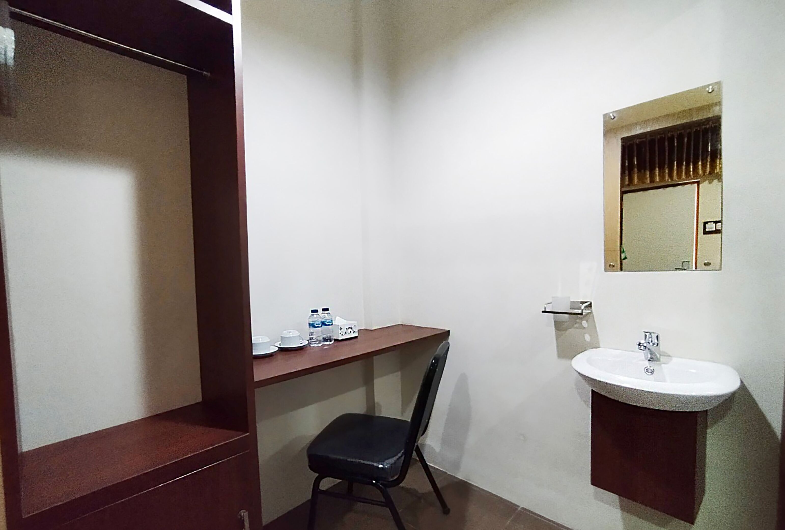 A small bathroom with a sink, mirror, and a chair.