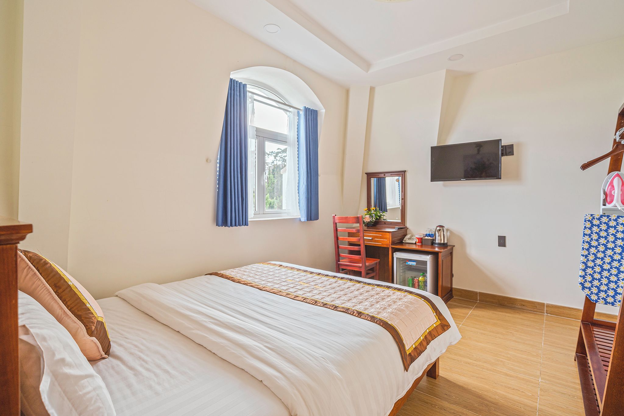 Ein Schlafzimmer mit einem Bett, einem Schreibtisch mit Stuhl, einem Fernseher und einem Kleiderschrank.