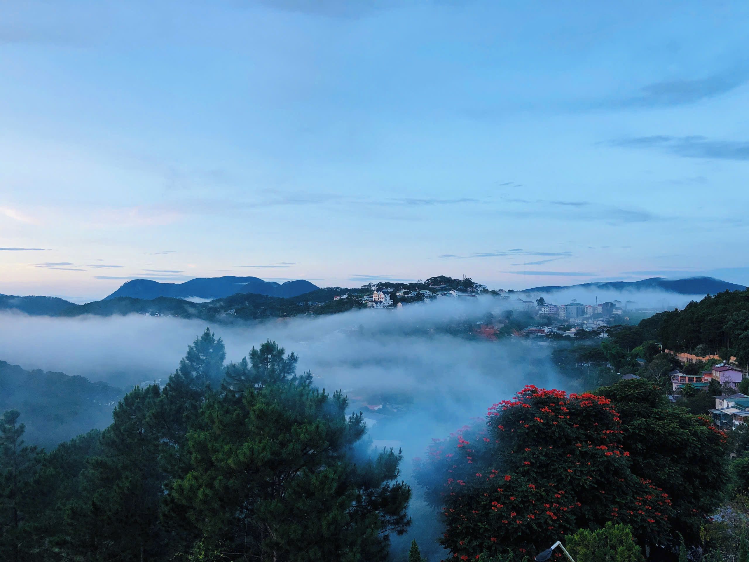 Un paisaje montañoso con un pueblo situado entre las colinas, rodeado de densa niebla.