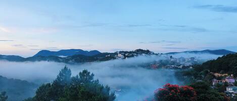Un paisaje montañoso con un pueblo situado entre las colinas, rodeado de densa niebla.