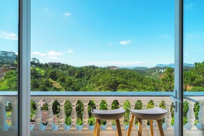 A balcony with two chairs overlooking a lush green landscape with hills and buildings. - Dieu Thong Hotel (Xuan Huong - Da Lat)