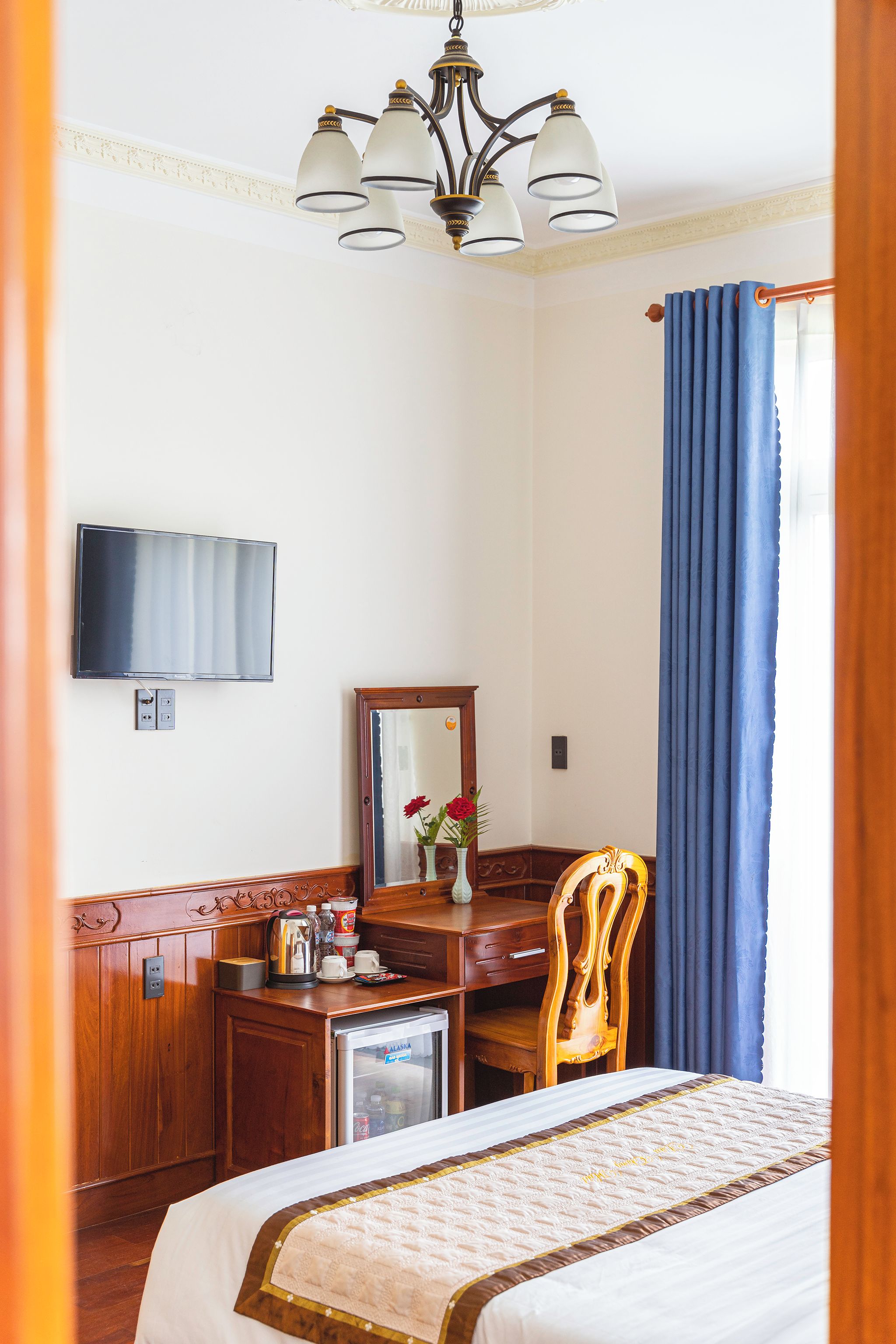 Ein Hotelzimmer mit einem Bett, einem Schreibtisch, einem Sessel, einem Fernseher und einer Minibar.