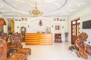 A reception area with a wooden reception desk, ornate furniture, and a chandelier. - Dieu Thong Hotel (Xuan Huong - Da Lat)