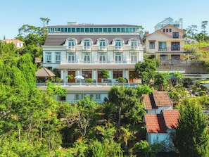 A multi-story building with a balcony, surrounded by lush greenery. - Dieu Thong Hotel (Xuan Huong - Da Lat)