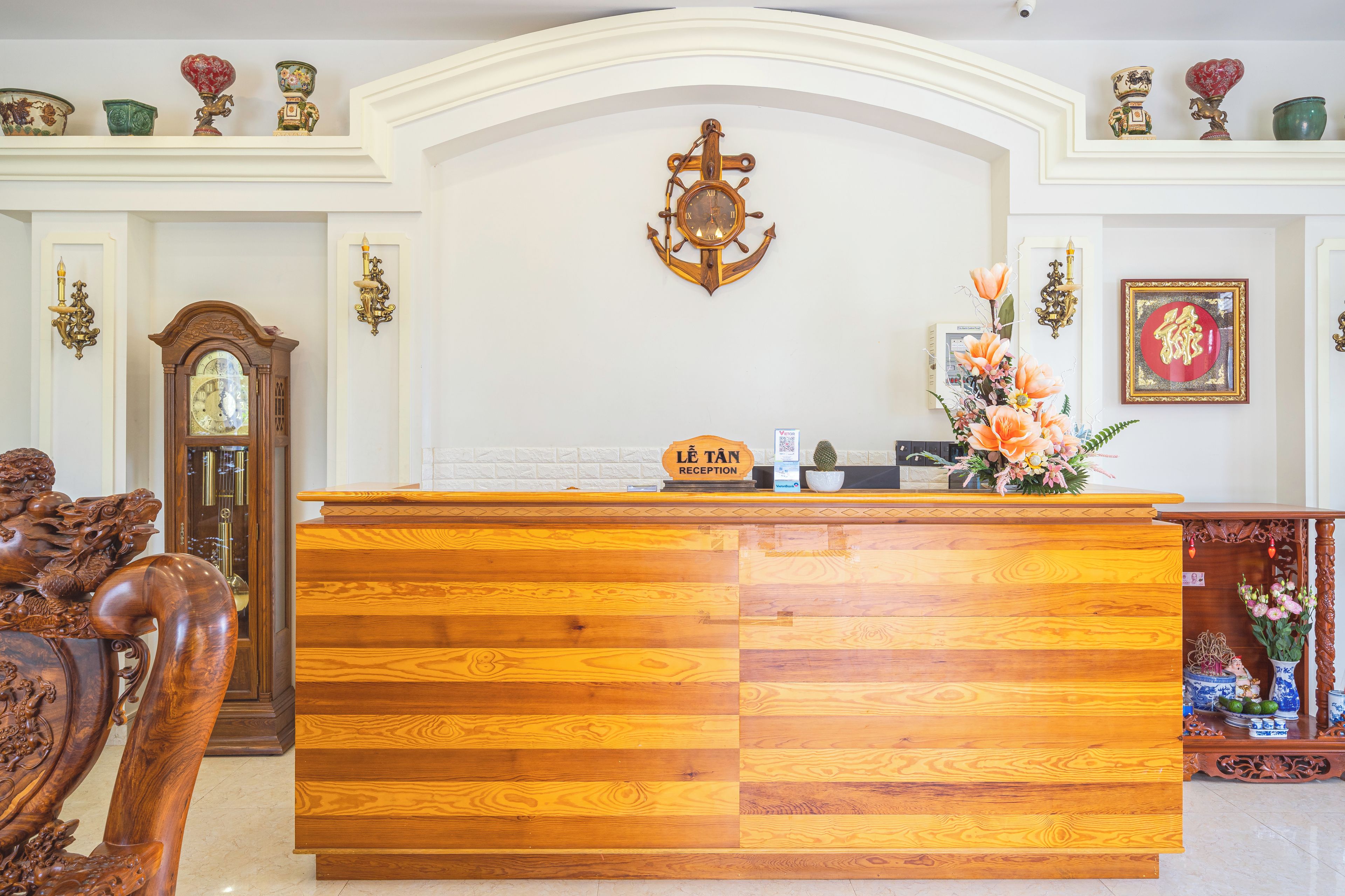 Una mesa de recepción con un reloj encima, rodeada de objetos decorativos y mobiliario.
