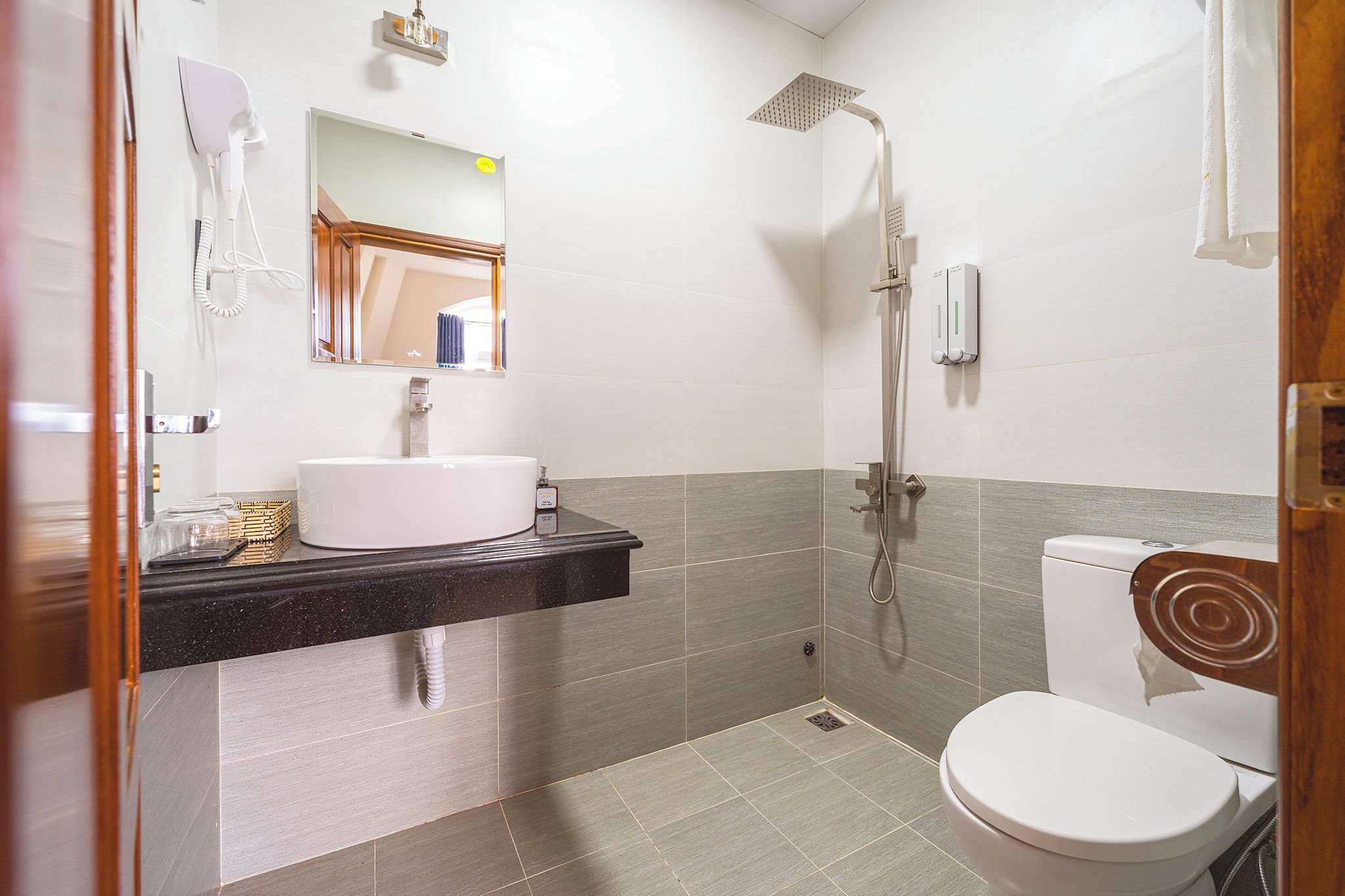 A bathroom with a white sink, a mirror, a shower, and a toilet.