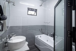 Executive appartement | Badkamer | Een haardroger, pantoffels, een bidet, handdoeken