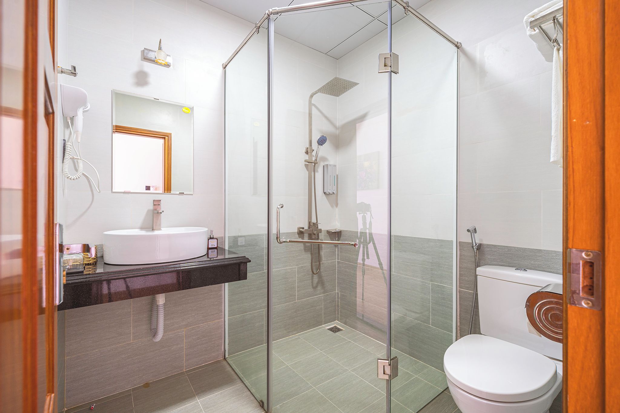 A modern bathroom with a glass-enclosed shower, a white sink, and a toilet.