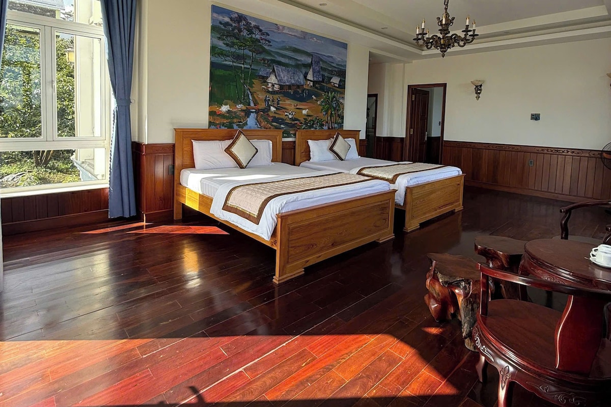 A spacious bedroom with a large bed, a dining table, and a painting on the wall.