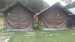 Two tents with numbers 9 and 8 on them, set in a grassy area with trees in the background. - Sukute Valley Resort (Kadambas)