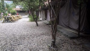 A gravel path leading to a covered seating area with chairs and a thatched-roof structure. - Sukute Valley Resort (Kadambas)