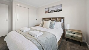 Une chambre d’hôtel avec un grand lit, une table de chevet et un tableau représentant un pont.