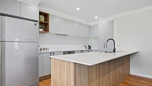 Une cuisine moderne dotée d’un îlot central, d’appareils électroménagers intégrés et d’un revêtement en bois.
