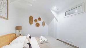 Une chambre à coucher moderne avec un lit, une lampe de chevet, des œuvres d’art murales et une fenêtre.