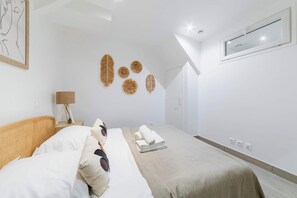 Ein modernes Schlafzimmer mit Bett, Nachttischlampe, Wandkunst und einem Fenster.