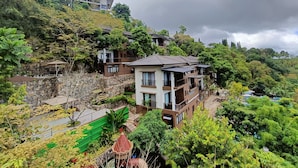 A hillside residential area with multi-story buildings, a stone retaining wall, and lush greenery. - Mist Mountain Resort powered by Cocotel (Cebu City)