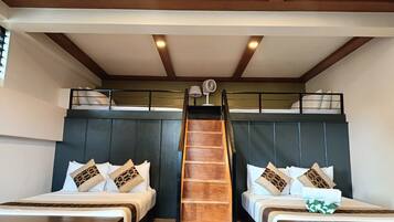 A room with two beds, a staircase, and a fan.