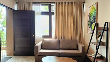 A room with a sofa, a coffee table, a ladder shelf, and a door leading outside.