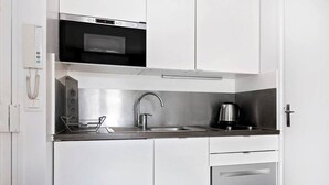 A compact kitchen with a built-in microwave, a coffee maker, and a stainless steel sink.