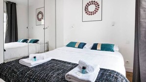 A hotel room with two beds, a large mirror, and a framed wreath on the wall.