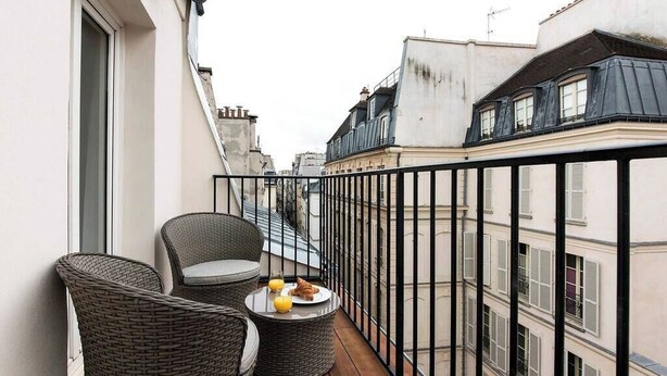 A balcony with wicker furniture and a table with food and drinks.