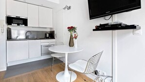 A modern kitchen with white cabinets, a microwave, and a flat-screen TV mounted on the wall.