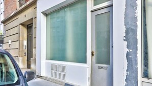 Un edificio con un gran ventanal, una puerta y una unidad de ventilación.