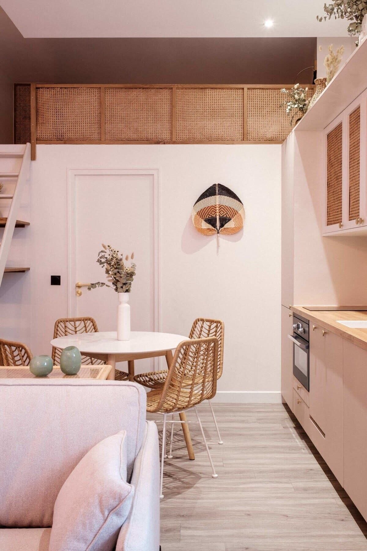 Una cocina compacta con zona de comedor, que incluye una mesa redonda, sillas de mimbre y una puerta blanca.