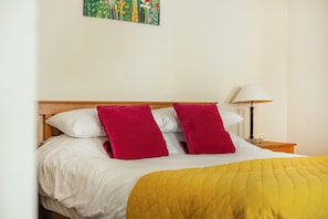 A bed with a wooden headboard, white bedding, and a yellow blanket. - Hay Store (Corwen)