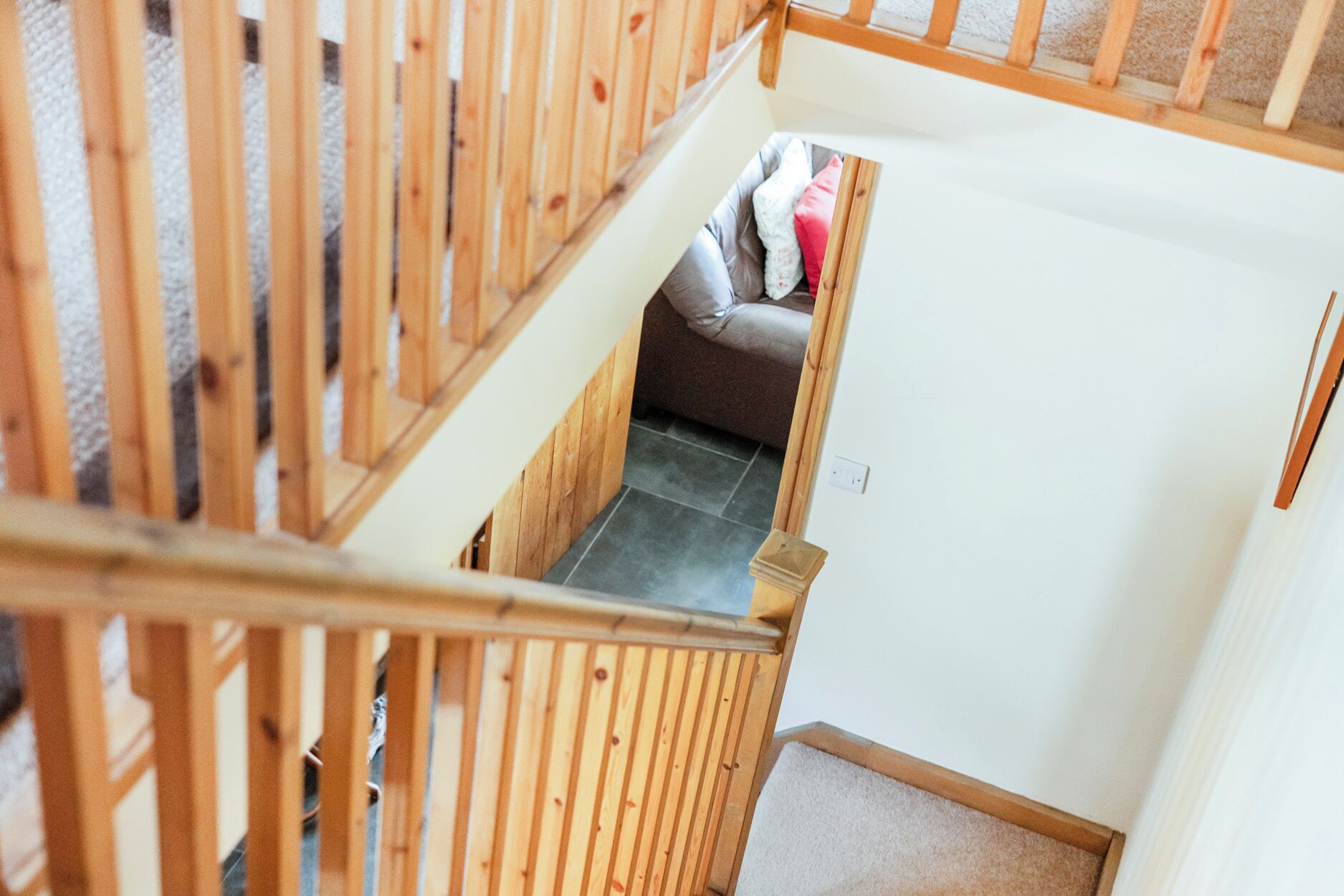 Una escalera de madera que conduce a una habitación con una cama y una alfombra pequeña.