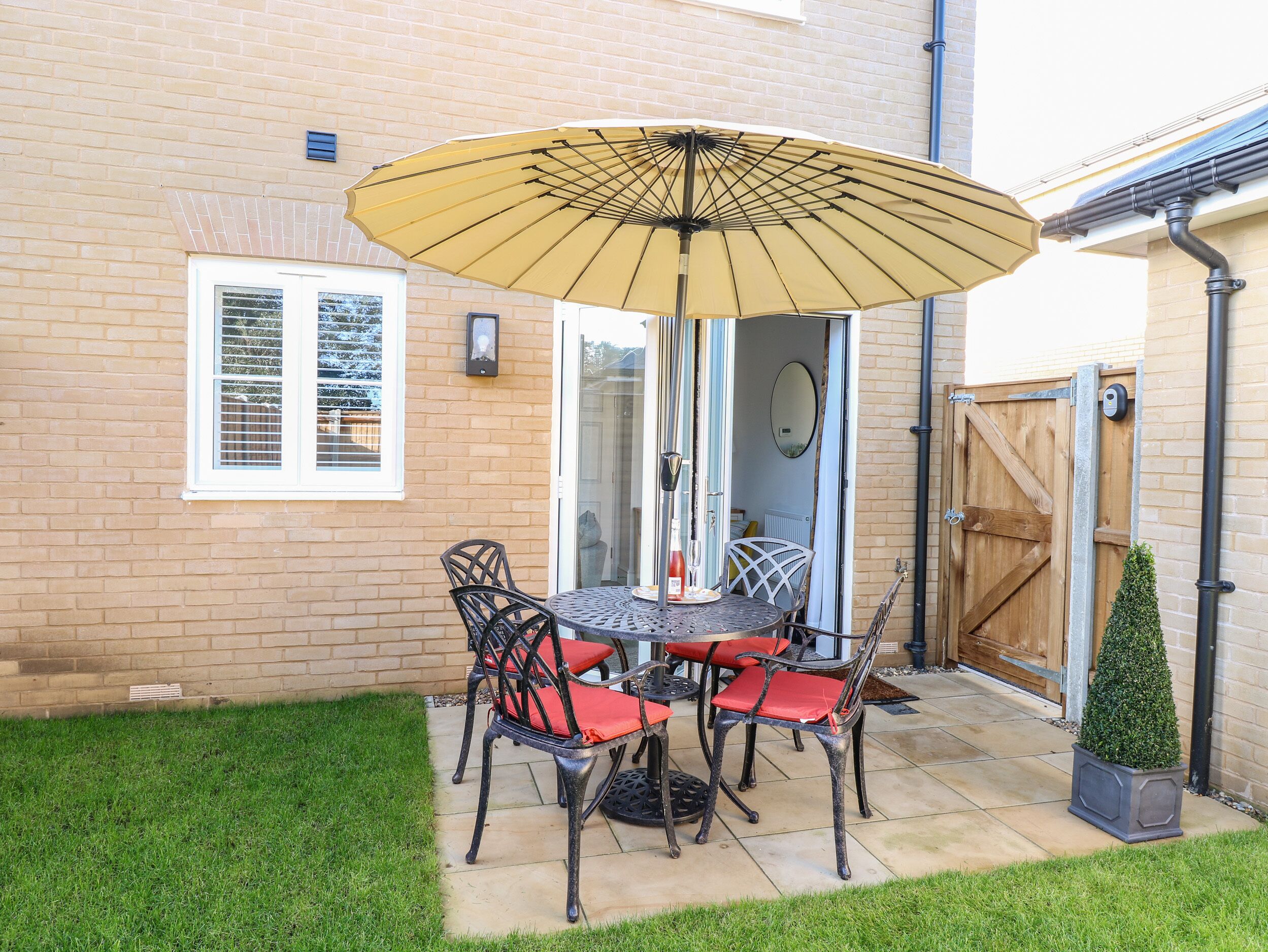 A patio with a table and chairs, a yellow umbrella, and a small potted plant.