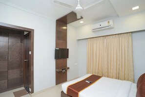 A hotel room with a bed, a television, an air conditioning unit, a ceiling fan, and a wardrobe. - HOTEL ZAIN GRANDE (Chennai)