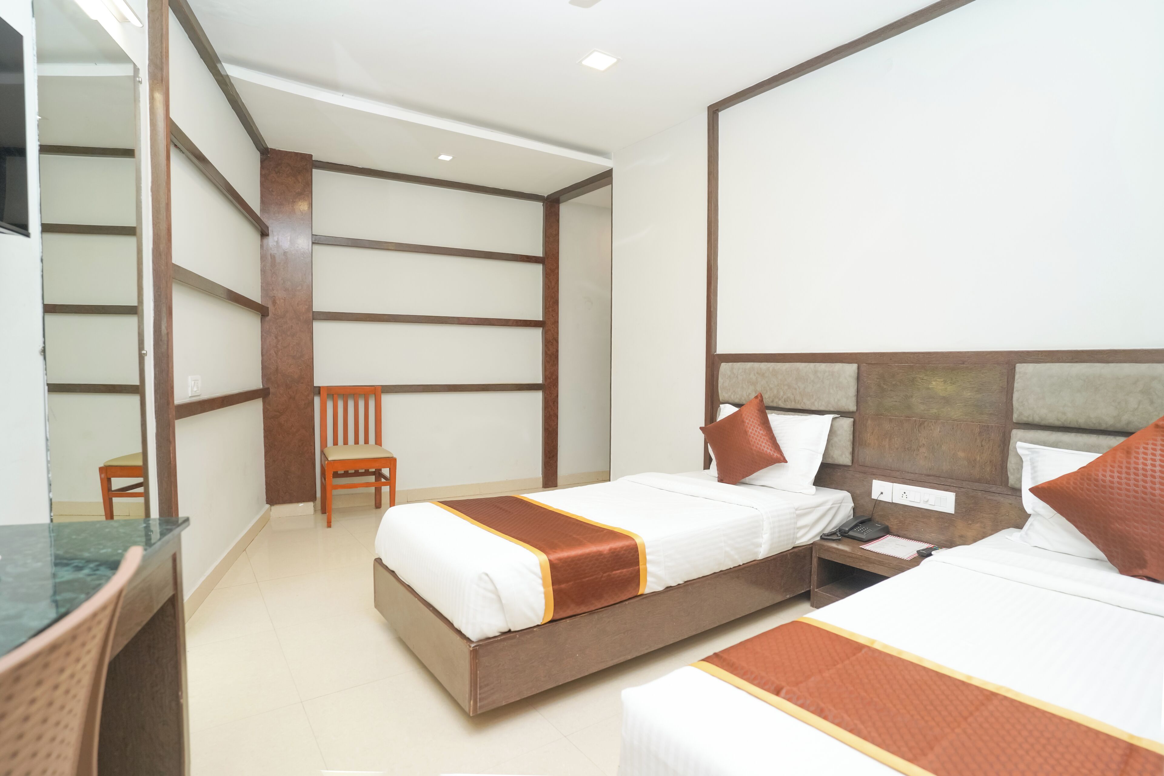 A hotel room with two beds, a desk, and a chair.