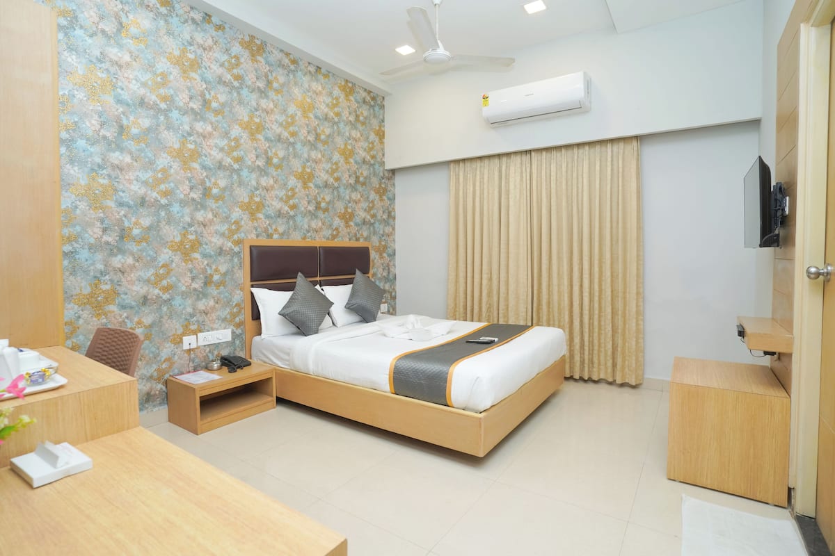 A hotel room with a bed, bedside table, desk, and a television.