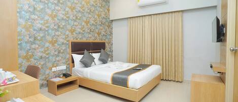 Una habitación de hotel con cama, mesita de noche, escritorio y televisión.