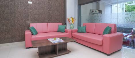 Una sala de estar moderna con dos sofás rosados, una mesa de centro de madera y un jarrón con flores.