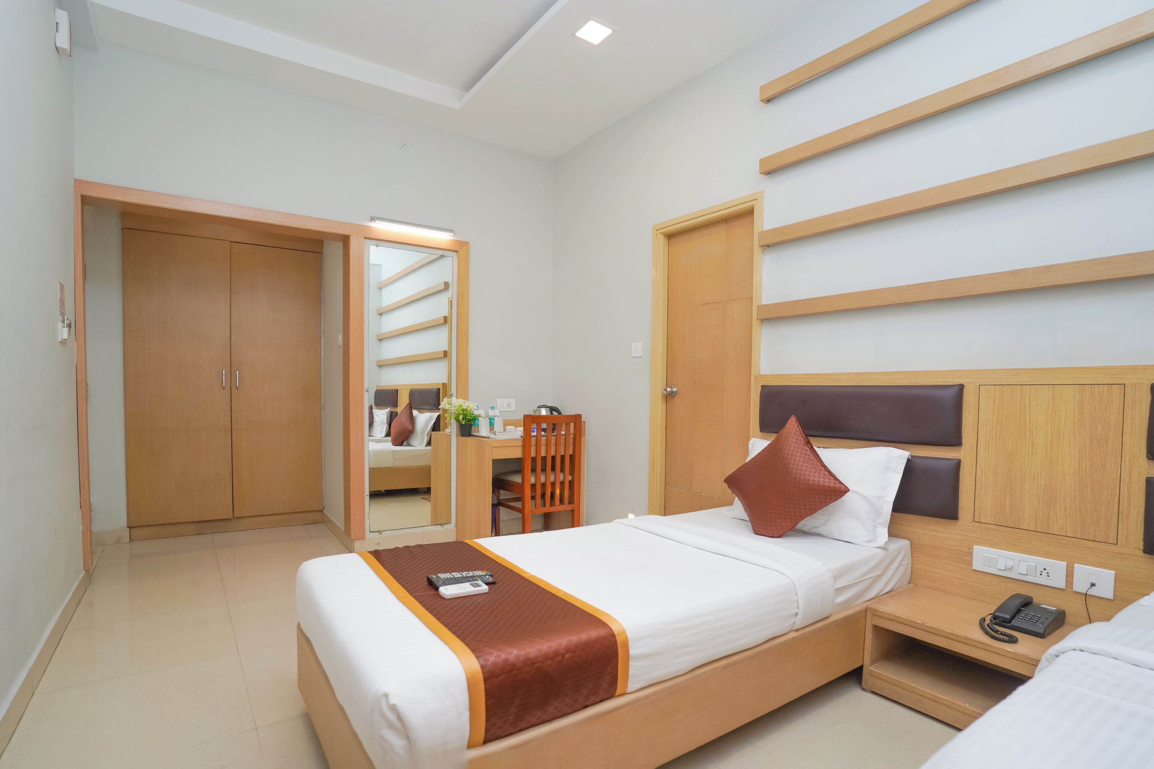 A hotel room with a bed, bedside table, and a desk with a chair.