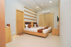 A modern bedroom with a large bed, bedside tables, a ceiling fan, and an air conditioning unit. - HOTEL ZAIN GRANDE (Chennai)
