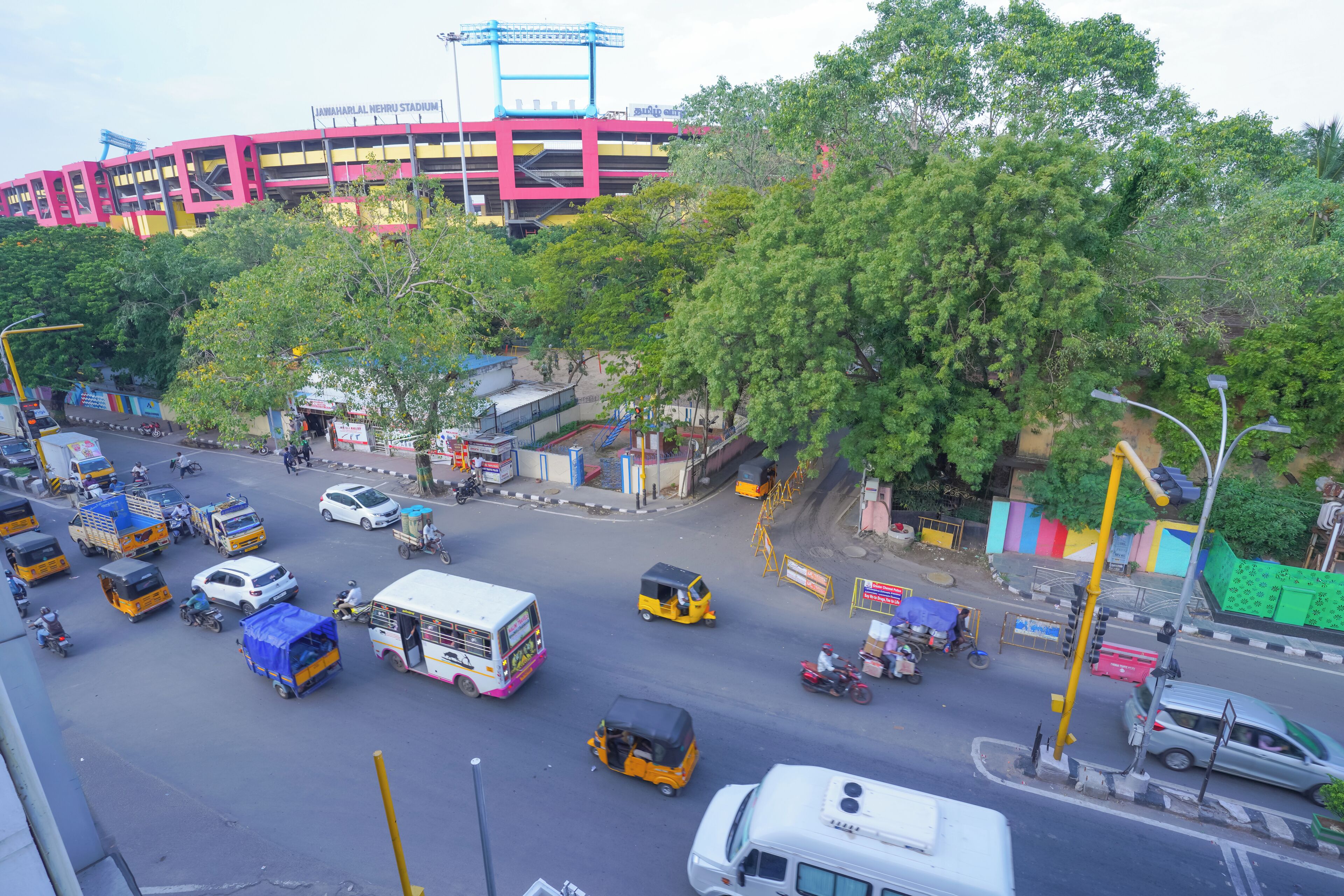 A busy urban street with various vehicles, including buses, cars, and auto-rickshaws.